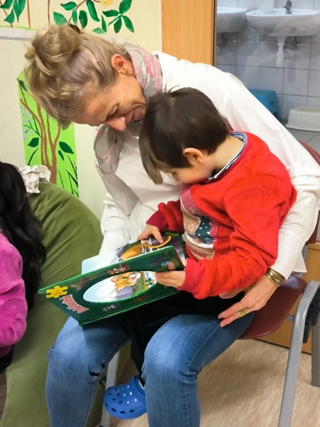 Egy kisfiú egy felnőtt ölében az ajándékba kapott könyvet nézi